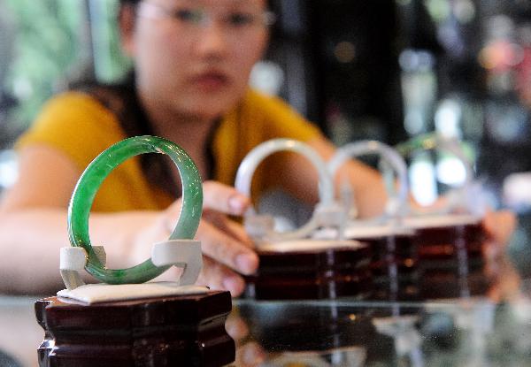 Photo taken on July 2, 2009 shows a worker displaying jade bracelets at a jewelry shop in Ruili City, Dai-Jingpo Autonomous Prefecture of Dehong, southwest China's Yunnan Province. Since the 1990s, Ruili has dedicated itself to developing the jewelry industry. There are over 6000 shops and 40,000 professionals engaged in jewelry industry in Ruili, with the annual trading volume reaching 2 billion RMB yuan. [Xinhua/Lin Yiguang]