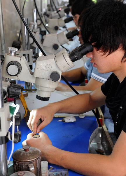 Workers polish the base of gem ornaments in Ruili City, Dai-Jingpo Autonomous Prefecture of Dehong, southwest China's Yunnan Province, May 26, 2011. Since the 1990s, Ruili has dedicated itself to developing the jewelry industry. There are over 6000 shops and 40,000 professionals engaged in jewelry industry in Ruili, with the annual trading volume reaching 2 billion RMB yuan. [Xinhua/Lin Yiguang]