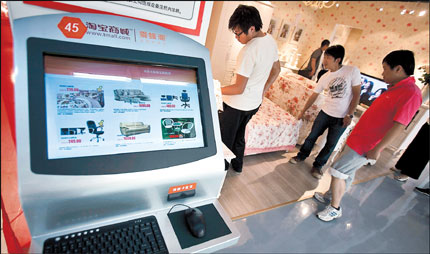 A computer screen displays various furniture items with their selling prices while Chinese shop inside the newlyopened Taobao Mall in Beijing. Taobao launched a five-story home furnishings showroom on Friday for customers to try out sofas, tables and other big-ticket items before placing an order online. [Shanghai Daily]