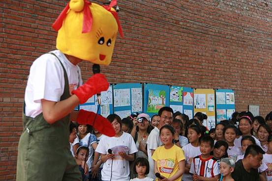 A volunteer dressed as a Tongxin mascot amuses the audience.