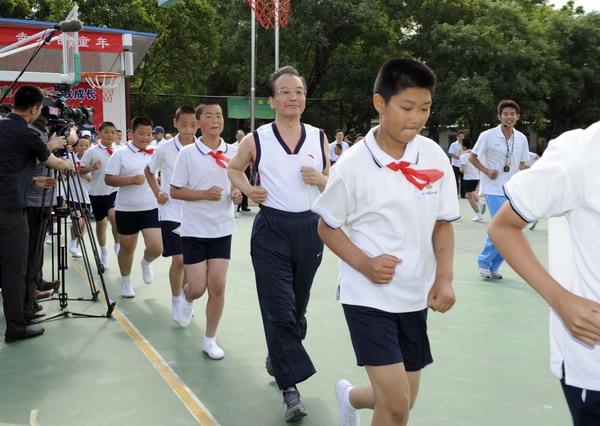 Premier Wen Jiabao (C) is seen during a warm-up activity at a PE class in Shibalidian primary school in Chaoyang district, Beijing, May 31, 2011. Wen pays a visit to the school Tuesday, where he joined students in a basketball game and encouraged children to stay healthy by participating in sports and other physical activities. [Xinhua]