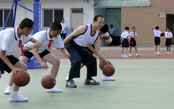 Premier Wen Jiabao plays basketball at a PE class in Shibalidian primary school in Chaoyang district, Beijing, May 31, 2011. [Photo/Xinhua] 