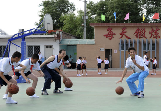 Premier Wen Jiabao plays basketball at a PE class in Shibalidian primary school in Chaoyang district, Beijing, May 31, 2011. [Xinhua] 