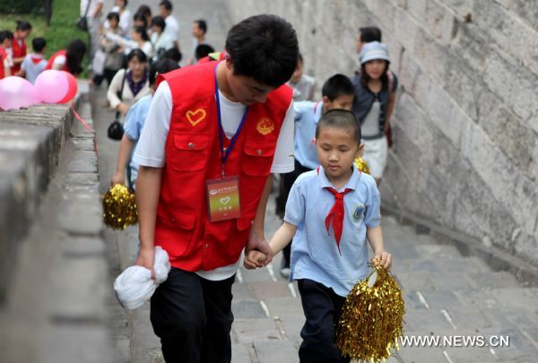 A boy with impaired sight steps onto the city walk under the help of a volunteer to take part in an celebration activity in Nanjing, capital of east China&apos;s Jiangsu Province, May 31, 2011. About 80 students from the school for blind children in Nanjing took part in an celebration activity of the upcoming International Children&apos;s Day on Tuesday by flying the kites they made. [Xinhua]