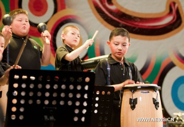 Autistic boy Chao Chao (R) plays the drums at the Chaoyang Theater in Beijing, capital of China, May 31, 2011. An art festival was held here to celebrate the International Children&apos;s Day. [Xinhua]