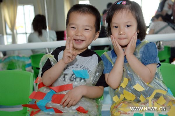 Two children show the dress they made in the Xinzhou Kindergarten in Binjiang District of Hangzhou, capital of east China&apos;s Zhejiang Province, May 31, 2011. The Xinzhou Kindergarten on Tuesday held a series of festivities for the children and their parents to celebrate the June 1 Children&apos;s Day. [Xinhua]