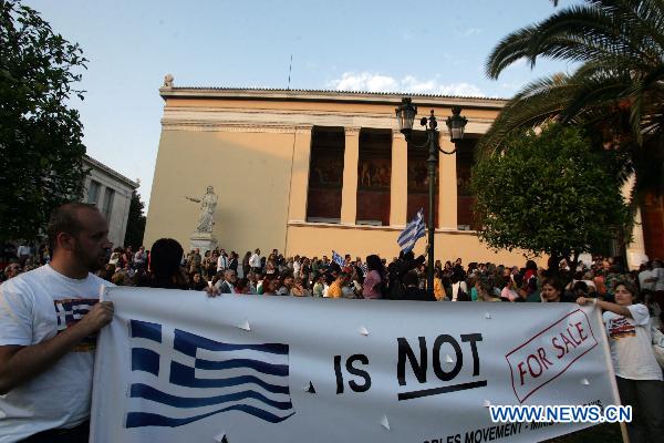 Greek protesters raise a banner with &apos;Greece is not for sale&apos; written on during a demonstration in front of the old university in Athens, Greece, on May 31, 2011. The protest was organized by Greek academics against austerity measures and was joined by thousands of Greek citizens. [Xinhua]