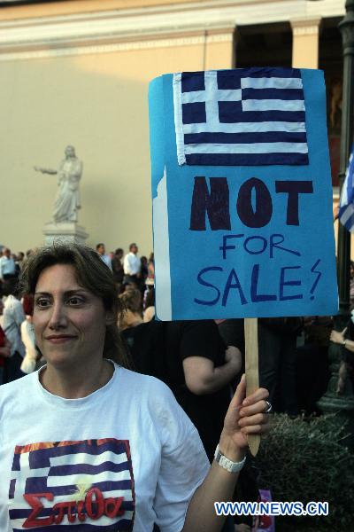 A Greek protester raises a banner with &apos;Greece is not for sale&apos; written on during a demonstration in front of the old university in Athens, Greece, on May 31, 2011. The protest was organized by Greek academics against austerity measures and was joined by thousands of Greek citizens. [Xinhua]