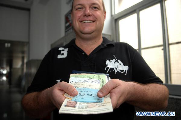 Daryl Paul, an Australian passenger, shows his passport and the train ticket with his passport number at the railway station in Hangzhou, capital of east China&apos;s Zhejiang Province, June 1, 2011. Chinese rail ticket offices started selling high-speed train tickets with passenger&apos;s name and ID numbers from June 1, 2011. [Xinhua]