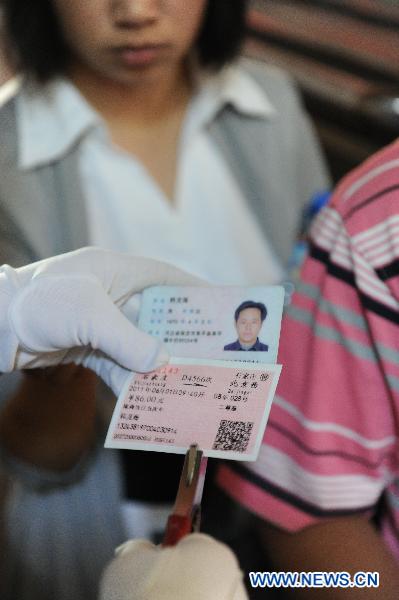Conductor verifies the ID card of a passenger while checking his ticket at the railway station in Shijiazhuang of north China&apos;s Hebei Province, June 1, 2011. Chinese rail ticket offices started selling high-speed train tickets with passenger&apos;s name and ID numbers from June 1, 2011. [Xinhua]