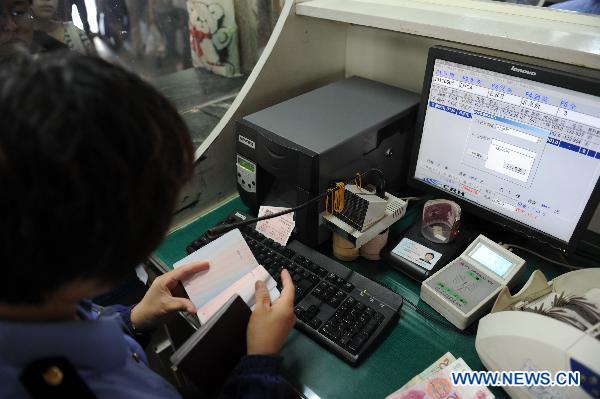 Staff member verifies the ID card of a passenger while selling ticket at the railway station in Shijiazhuang of north China&apos;s Hebei Province, June 1, 2011. Chinese rail ticket offices started selling high-speed train tickets with passenger&apos;s name and ID numbers from June 1, 2011. [Xinhua]