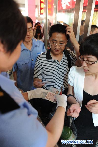 Conductor verifies the ID card of a passenger while checking her ticket at the railway station in Shijiazhuang of north China&apos;s Hebei Province, June 1, 2011. Chinese rail ticket offices started selling high-speed train tickets with passenger&apos;s name and ID numbers from June 1, 2011. [Xinhua]