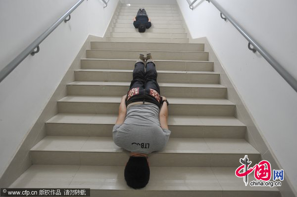 Two men plank on stairs in a building in Shenyang, May 31, 2011. [Photo/CFP]