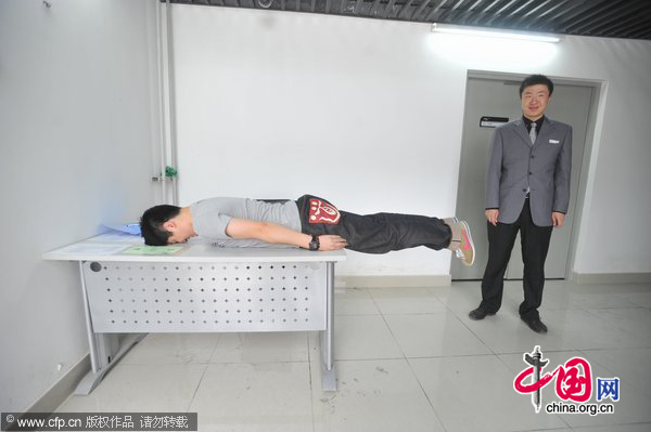 A man planks on a table in an office building in Shenyang, May 31, 2011. [Photo/CFP]