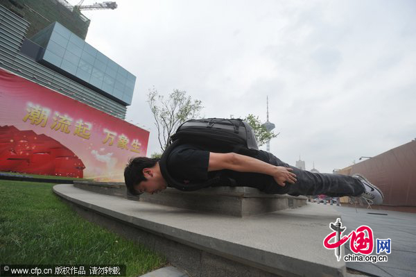 A man planks on the edge of a flower bed in Shenyang, May 31, 2011. [Photo/CFP]