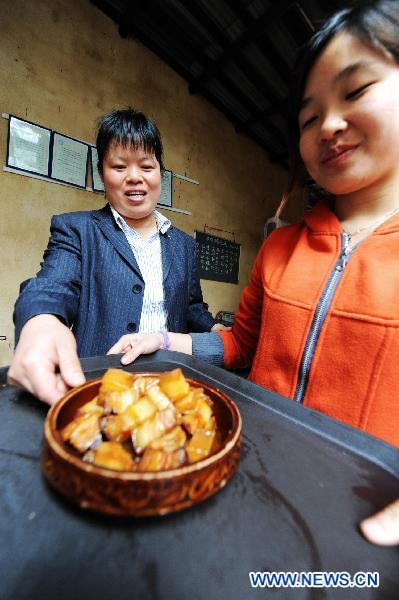 Hostess Peng Xuequn (L) and a waitress serve braised pork for customers at Shaoshan Ren Jia, or literally Shaoshan-Household Restaurant, in Shaoshan, central China's Hunan Province, May 24, 2011. [Xinhua/Long Hongtao]