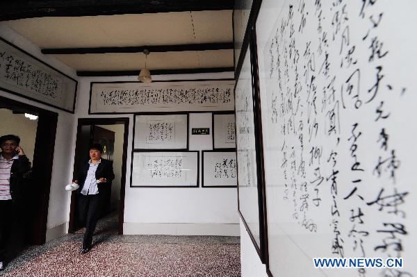  Hostess Peng Xuequn (R) walks past decorations with poems or quotations of Chairman Mao at her Shaoshan Ren Jia, or literally Shaoshan-Household Restaurant, in Shaoshan, central China's Hunan Province, May 24, 2011. [Xinhua/Long Hongtao]