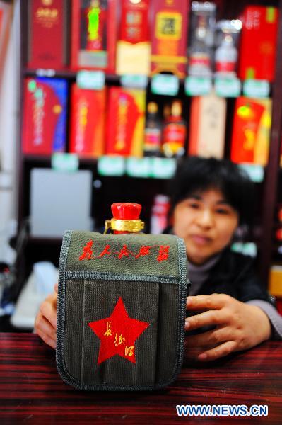 A waitress presents a bottle of specially packed liquor at Shaoshan Ren Jia, or literally Shaoshan-Household Restaurant, in Shaoshan, central China's Hunan Province, May 24, 2011. [Xinhua/Long Hongtao] 
