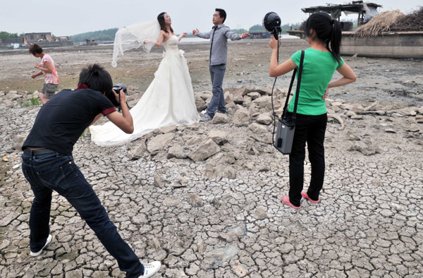 A bride and groom stand on the dried-up bed of Huaihe River in Xuyi, Jiangsu province, on Monday for their wedding photos. The water level in the middle of Huaihe River that day had fallen to 12 meters, the lowest level on record. [China Daily] 