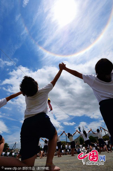 A halo appears around the sun over children performing gymnastic exercises during a local school sports meet in Minami-Ashigara, Kanagawa Prefecture, about 70km southwest of Tokyo, on Tuesday, May 31, 2011. The atmospheric phenomenon called a 22-degree halo of the son is caused when sunlight is refracted in hexagonal ice crystals suspended in the atmosphere. [CFP]