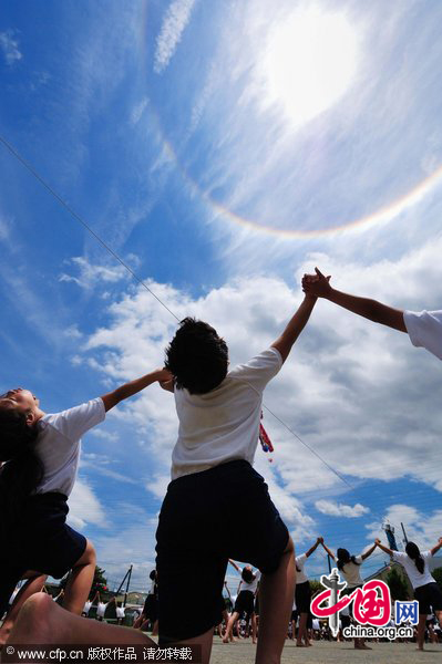 A halo appears around the sun over children performing gymnastic exercises during a local school sports meet in Minami-Ashigara, Kanagawa Prefecture, about 70km southwest of Tokyo, on Tuesday, May 31, 2011. The atmospheric phenomenon called a 22-degree halo of the son is caused when sunlight is refracted in hexagonal ice crystals suspended in the atmosphere. [CFP]