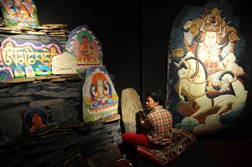 An inheritor shows skills to make Tibetan nationality King Gesar painted rock carvings at the International Intangible Cultural Heritage Expo Garden in Chengdu, May 29, 2011. [Xinhua] 一位传承人在成都国际非物质文化遗产博览园内展示藏族格萨尔彩绘石刻技艺（5月29日摄）。[新华社]