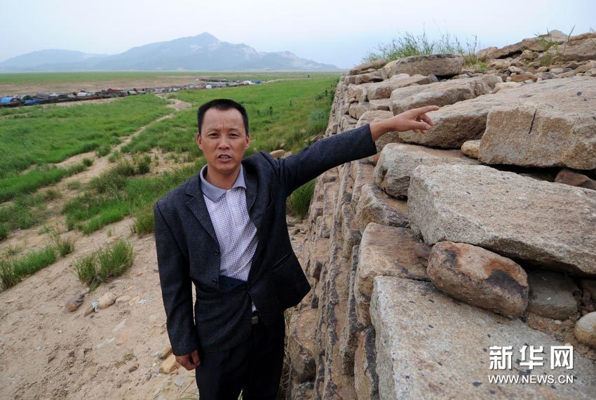 The water level of Poyang Lake is supposed to be the height where the man is pointing at. [Xinhua]