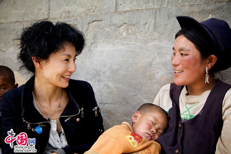 Maggie Cheung, UNICEF Ambassador in China talks with a woman of Yi ethnic group. Her husband died in a traffic accident, leaving behind four children all to her shoulders. The village’s child welfare director often visited her family and called on others to help her with farm work during the past year. [UNICEF]