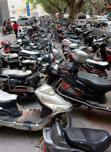 Electric scooters are parked on a sidewalk in Zhengzhou, the capital of Central China&apos;s Henan province, in this file photo taken May 17, 2011. [Xinhua] 