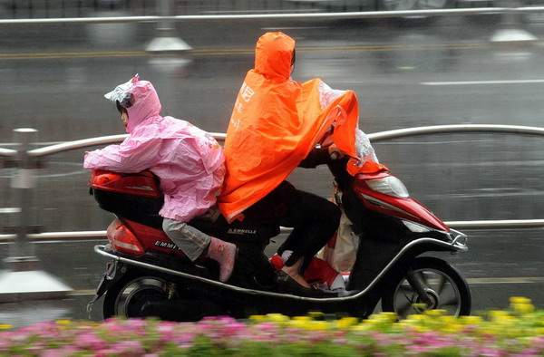 A woman carries a girl on her electric scooter in the rain in Zhengzhou, Central China&apos;s Henan province, in this file photo taken May 10, 2011. [Xinhua] 