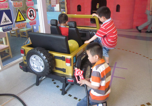 A young boy adds gas to a play car, while his friends jump in for a ride at the Magic Bean House in Beijing. [Photo:CRIENGLISH.com]