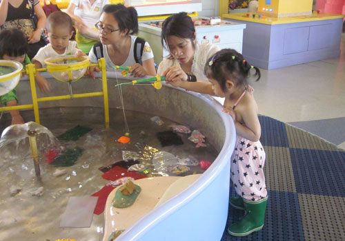Children try fishing at the water table under their mothers' guidance at the Magic Bean House. [Photo:CRIENGLISH.com]