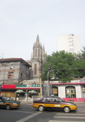 St. Michael's Church peers out from behind convenience stores on a busy Taijichang Street. [Photo:CRIENGLISH.com]