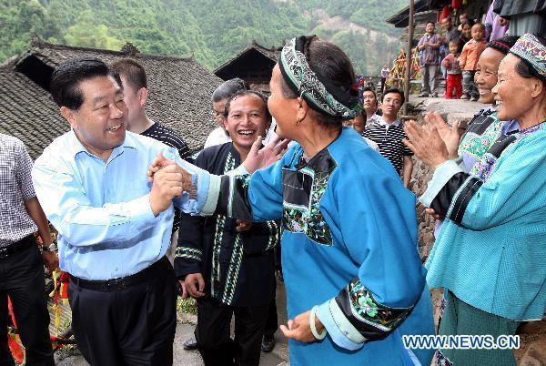 Jia Qinglin (L front), a member of the Standing Committee of the Political Bureau of the Communist Party of China (CPC) Central Committee, who is also chairman of the Chinese People's Political Consultative Conference (CPPCC) National Committee, visits residents of ethnic minorities in Maoping Village, Morong Town of Guzhang County in central China's Hunan Province, June 2, 2011. Jia paid an inspection visit in Guizhou Province, Chongqing Municipality and Hunan from May 31 to June 4. [Yao Dawei/Xinhua]