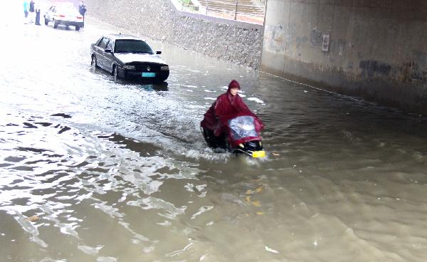 Vehicles pass the pool of water on a flooding road in Ruichang of Jiujiang City, east China's Jiangxi Province, June 4, 2011. A rainstorm hit most parts of Jiujiang on Saturday. The rainfalls, to last until Monday, will greatly ease the drought the area has suffered for months. [Wei Dongsheng/Xinhua]