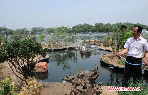 Qu Xisheng waters the plants on the duck shelter in Shichahai, a lake in the Chinese capital's downtown, in Beijing, June 6, 2011. Some 10 years ago, citizen Qu Xisheng built a duckhouse for a brood of wild ducks here over the lake. With his 10-year-effort and the help of local government, the duckhouse had developed into a 158 square meters large island, providing a shelter for over 100 birds including wild ducks, mandarin ducks, and night herons. [Xinhua/Wang Zhen] 