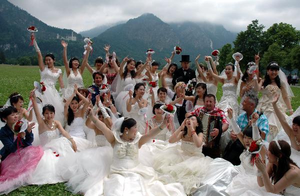Chinese brides taking part in a collective wedding event pose for photographs in a field in front of New Swan Stone Castle in Fuessen, south Germany, on June 3, 2011. A total of 31 couples from north China's Tianjin Municipality held a collective wedding on Friday at New Swan Stone Castle, one of the most popular travel destinations in Europe. [Xinhua/Wu Mei]