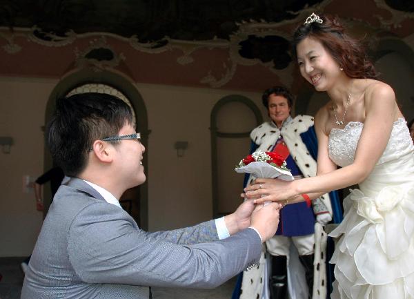 A chinese bridegroom presents flowers to his bride during their collective wedding at New Swan Stone Castle in Fuessen, south German, on June 3, 2011. A total of 31 couples from north China's Tianjin Municipality held a collective wedding on Friday at New Swan Stone Castle, one of the most popular travel destinations in Europe. [Xinhua/Wu Mei] 