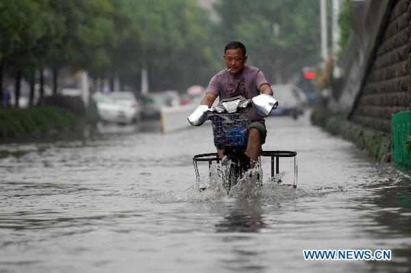 A man wades with his electric scooter on the flooded street in Hangzhou, capital of east China&apos;s Zhejiang Province, June 6, 2011. Continued rainfall hit Hangzhou in recent days, disturbing the city&apos;s traffic. Multiple places in Zhejiang have been suffering from drought since spring of this year.