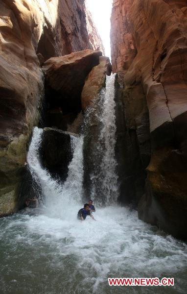Hikers stand in front of a waterfall at Jordan's Wadi Al Mujib natural reserve, which is also called the Grand Canyon of Jordan, 40km south of Jordan's capital Amman, on June 7, 2011. [Xinhua/Mohammad Abu Ghosh] 