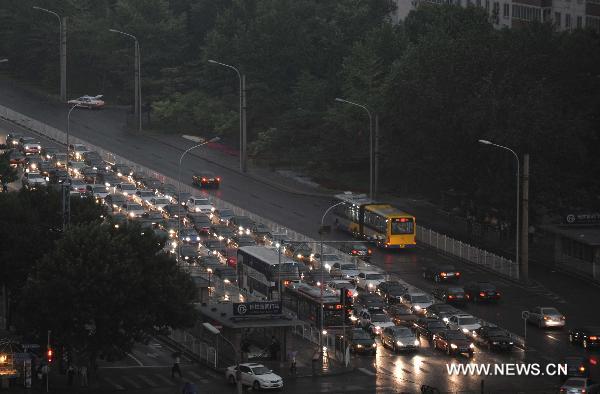 Drivers turn on their lights as thunderstorm poured in Beijing, capital of China, at dusk on June 7, 2011. [Xinhua]