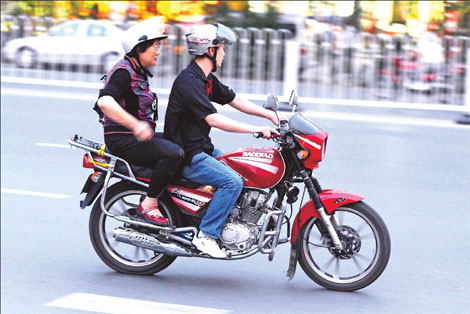 A motorcycle taxi takes a passenger along Linquan Road, one of the busiest streets in Hefei, capital of Anhui province. These unofficial taxis are popular because they can zip between all the cars stuck in traffic.