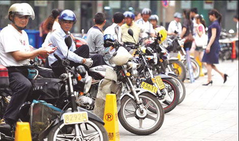 Motorcyclists wait for customers on Huaihe Road in Hefei.