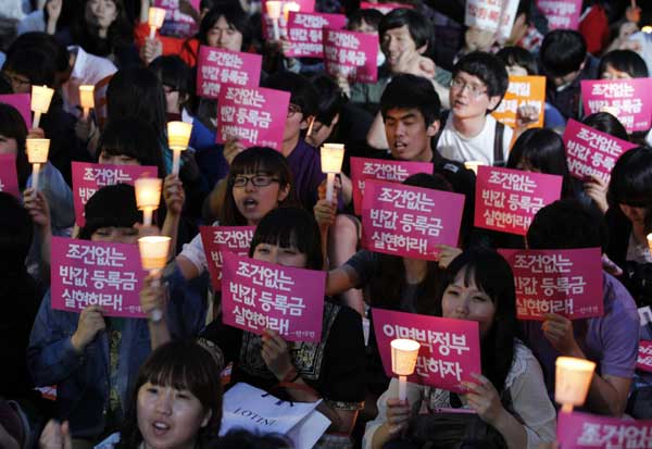  University students holding candles shout slogans during a rally demanding tuition fee cuts, at the Cheonggye stream plaza in central Seoul June 7, 2011. [China Daily/Agencies]