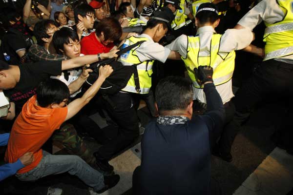 Protesters drag police officers trying to block the protesters&apos; march during a rally demanding tuition fees cuts on a street in central Seoul, June 7, 2011. [China Daily/Agencies]