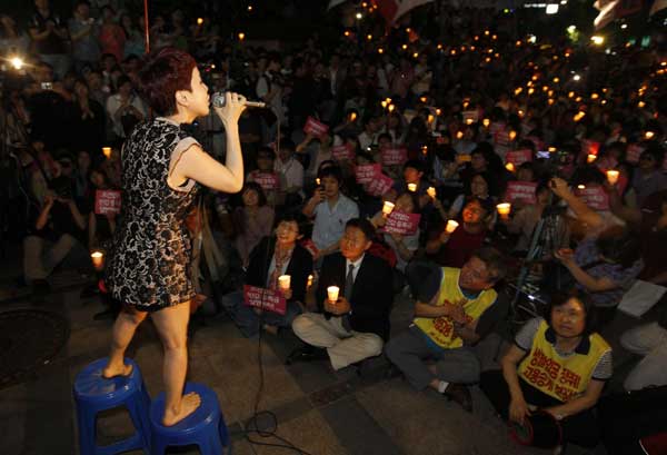 K-pop singer Park Hye-kyoung sings during a candle-lit rally demanding tuition fee cuts, at the Cheonggye stream plaza in central Seoul, June 7, 2011.[China Daily/Agencies]