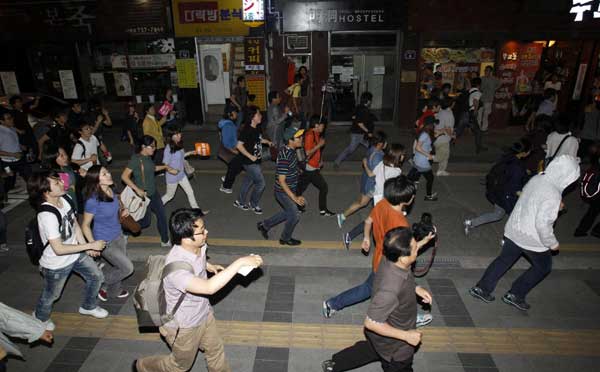 Protesters run during a rally march demanding tuition fees cuts on a street in central Seoul June 7, 2011. [China Daily/Agencies]