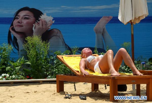 A tourist enjoys the sun-bath on the man-made beach in Shanghai, east China, June 9, 2011. Local weather station issued a high temperature warning on Thursday. The high temperature in Shanghai on Thursday reached 37 degrees centigrade. [Xinhua] 