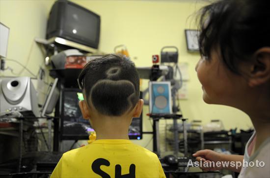 The Apple logo has been shaved into the hair of five-year-old boy Taotao, who plays computer games inside a shop in Qianxiang county, Dongyang city, Zhejiang province, on June 6, 2011. The Apple craze is catching on in China, with many citizens now using the company's products.