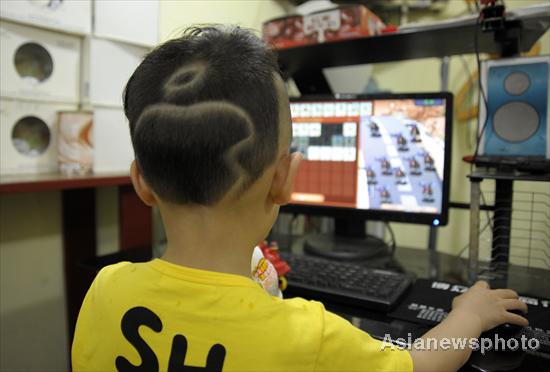 The Apple logo is seen on the back of the head of a five-year old boy, Taotao, who plays computer games inside a shop in Qianxiang county, Dongyang city, Zhejiang province, on June 6, 2011. [Photo/Asianewsphoto]